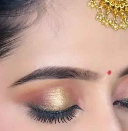 A detailed shot of a soft-cut crease with a gold shimmer. This technique adds dimension to the eyes and is a popular choice for bridal and reception makeup.