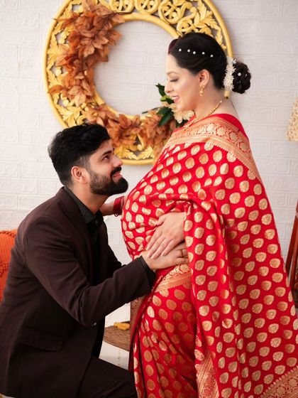 A pose full of reverence and love. The husband-to-be kneels before his wife, his hand gently on her belly, looking up at her with adoration.