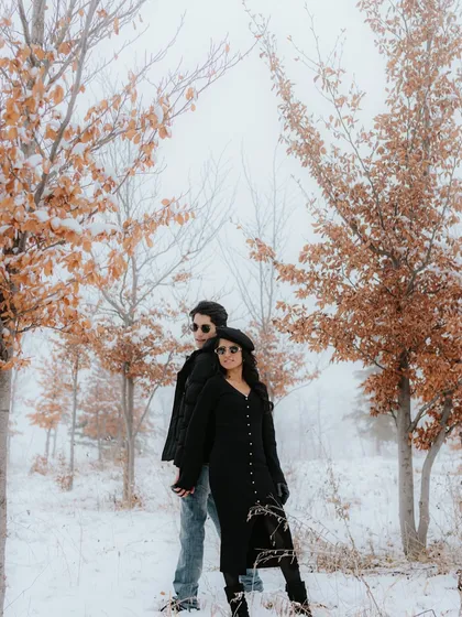 A moody, atmospheric shot of a couple standing back-to-back amidst snow-dusted trees in Azerbaijan. The fog and autumn leaves add a touch of mystery and romance to their pre-wedding story.