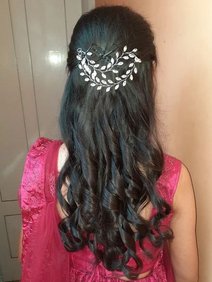 Simple and elegant curls styled in a half-updo. This look is secured with a beautiful silver leaf-design hair clip, making it perfect for guests or bridesmaids.