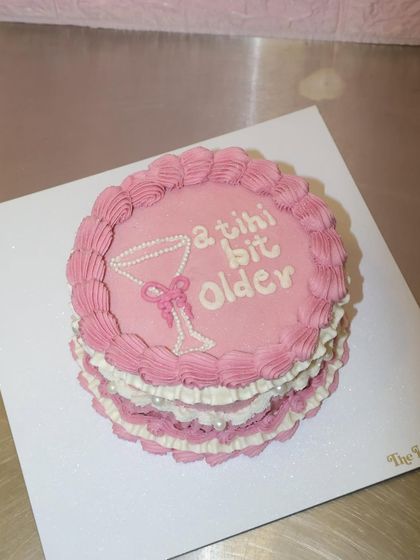 Another view of our "a tini bit older" cake, showcasing the delicate layers of pink and white piped ruffles.