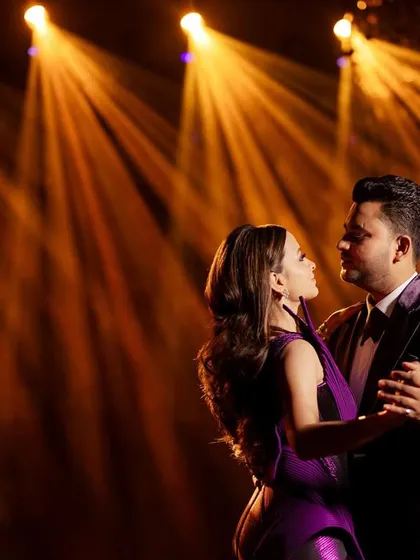 Dancing under the spotlight. This image captures the flow and structure of the bride's gown and the classic cut of the groom's tuxedo, perfect for their first dance.