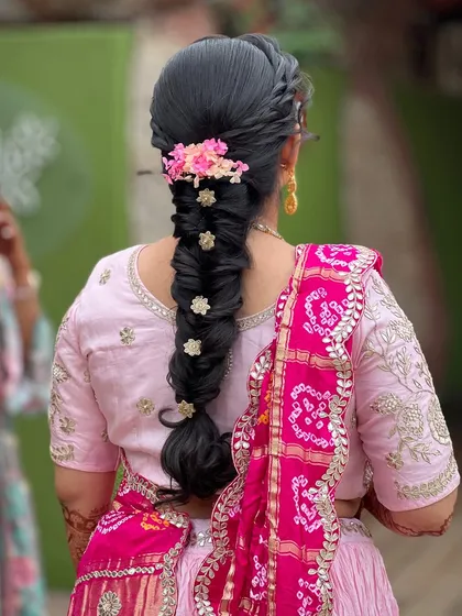 A detailed view of the intricate braided hairstyle, adorned with delicate pink and white flowers.