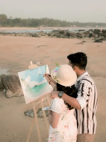 A close-up of the couple painting together on the beach. This shot focuses on the collaborative and creative aspect of their relationship.