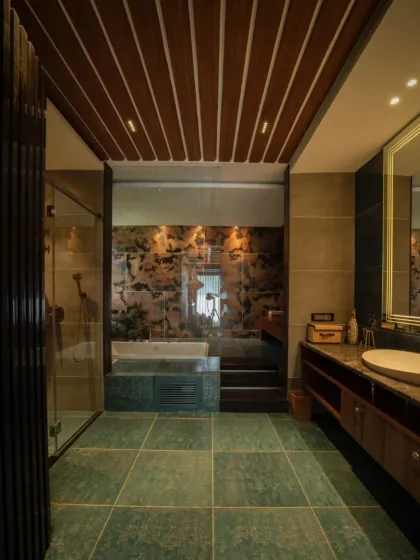 Another view of the rustic-modern bathroom, showing the glass partition for the shower and the step-up to the tub area, highlighting the layered design.