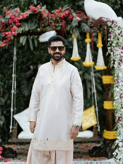A full-length shot of the groom's stylish Haldi outfit, perfectly complementing the lush, floral decor we designed.