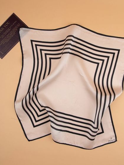 The striped pocket square draped next to a brand card, showing the fabric's flow.