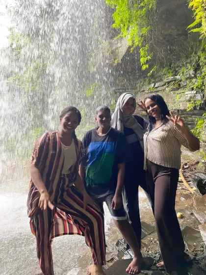 Four friends enjoying their time behind a curtain of water at the falls.