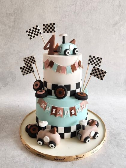 A vintage race car-themed cake for Krianshh's 4th birthday. The checkered flags and retro-style cars give it a classic feel.