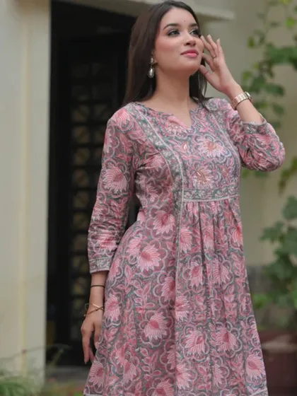 A pink and grey block-printed dress with a gathered waist. This design is flattering and comfortable, showcasing a softer color palette for ethnic wear.