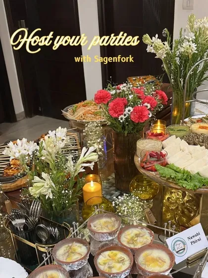 A beautifully lit grazing table set for a Diwali party. The spread includes appetizers, salads, and desserts like Nawabi Phirni, all adorned with fresh flowers and candles to create a warm, festive ambiance.