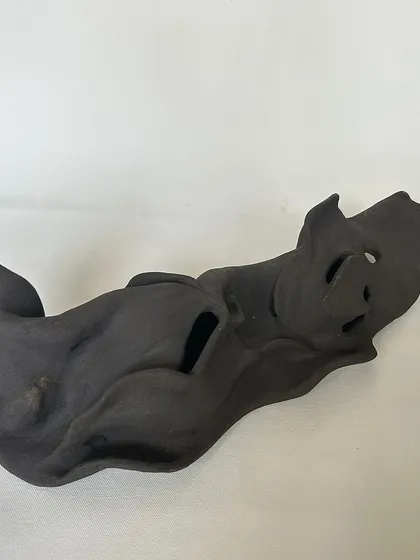 A different angle of the same dark clay sculpture, highlighting its fluid, ribbon-like form. Each view reveals something new.