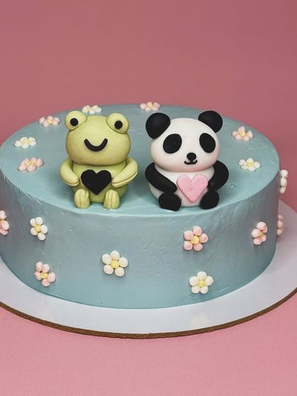 "Tu hai toh I'll be alright". This adorable cake features a cute fondant frog and panda holding hearts. It's a sweet and simple design for celebrating a special friendship or relationship.