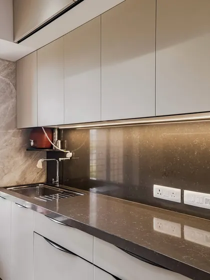 The sink area of the Kandivali kitchen, featuring an under-mount sink and profile lighting that illuminates the workspace.