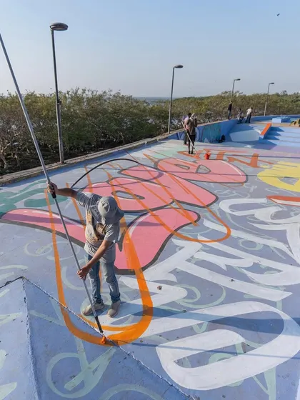 Using an extension pole to paint the large letterforms on the ground. This tool is essential for maintaining perspective and clean lines on huge surfaces.