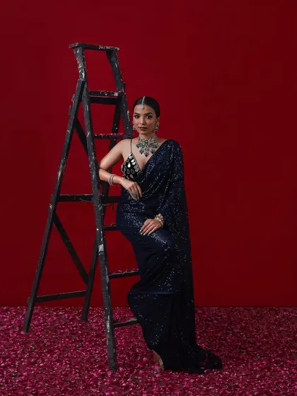A modern and glamorous reception look with a sequined navy blue saree and sparkling silver jewelry.