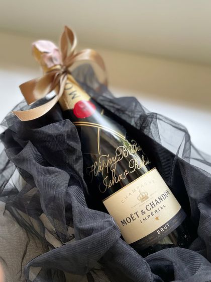 A styled shot of the calligraphed Moët bottle, nestled in black tulle. It's a simple way to make a celebratory gift feel extra luxurious and personal.