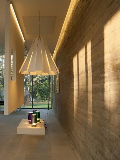 This shot highlights the play of natural light on a rammed earth wall within the experience center. The design uses natural materials and dramatic lighting to create a space that is both elegant and grounded.