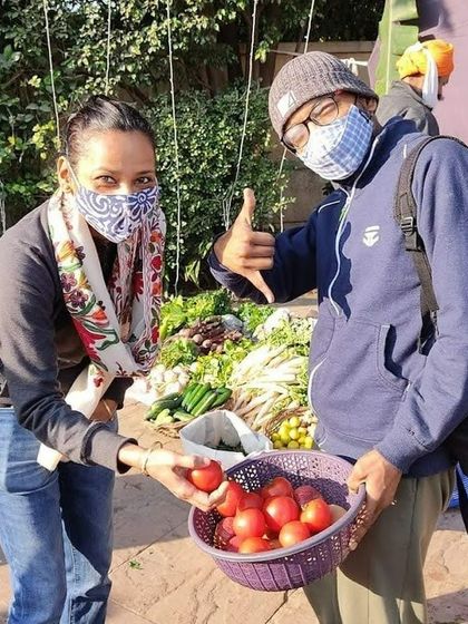 A customer holding a basket of tomatoes, with a thumbs-up from another shopper.