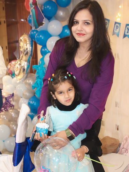 A mother and daughter pose together with a themed cupcake during a birthday party.