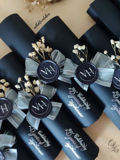 A collection of the finished invitation scrolls, each tied with a silver ribbon and adorned with a custom wax seal and dried baby's breath for a touch of softness.
