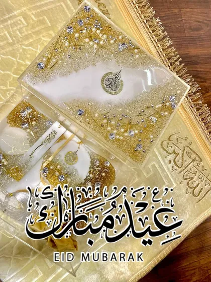 An elegant gift set in white and gold, perfect for Eid or any special occasion. This set includes a resin Quran box, a matching bookmark, and other accessories, all embellished with crystals and pearls for a luxurious finish.
