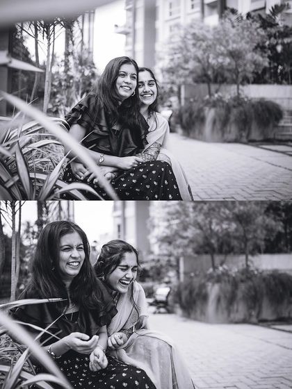 A black and white photo capturing the genuine laughter and friendship between two sisters sitting together outdoors.