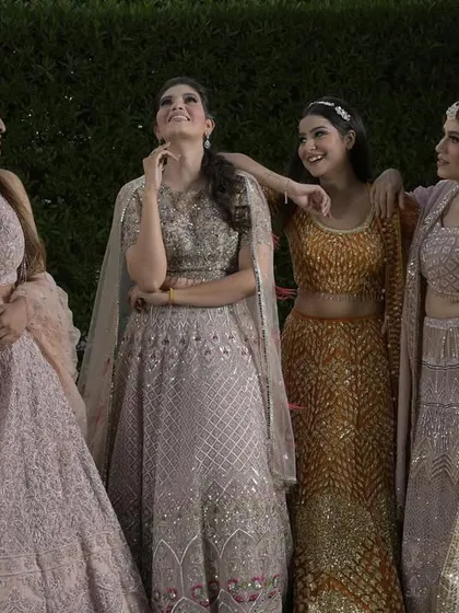 A candid moment between friends, all dressed in our gorgeous pastel and golden lehengas. This image captures the joy and camaraderie of a wedding celebration.