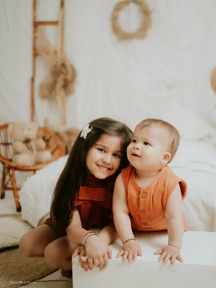A sweet moment between siblings. The warm, neutral tones of the setup create a cozy and inviting atmosphere.