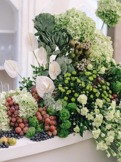 A stunning bar arrangement featuring a cascade of green hydrangeas, white anthuriums, grapes, and figs.