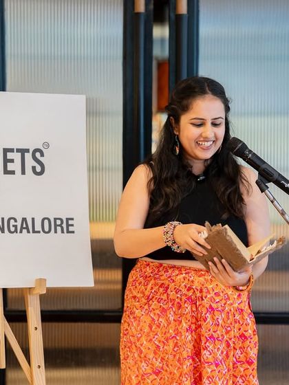 A poet reads from her journal, a smile on her face. The event was a celebration of the love and stories that mothers inspire.