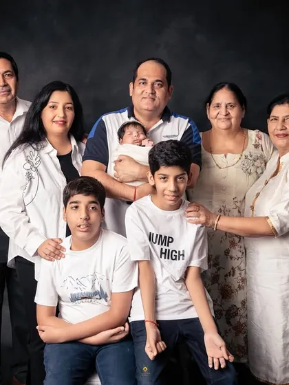 A large, multi-generational family portrait against a classic dark backdrop. It’s a powerful image that brings together three generations to celebrate the family's newest addition.