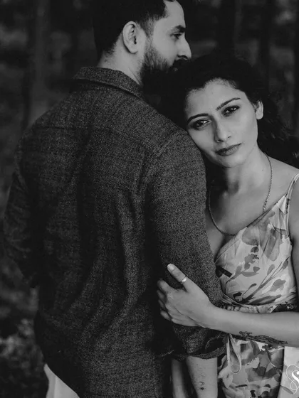 A powerful and emotive black and white portrait. Her direct gaze and the protective embrace create a fine-art image that is both strong and tender.
