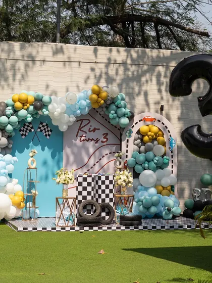 Another angle of the fantastic race car setup, showing the large number "3" and the balloon-filled archway. The green lawn provides a great contrast to the decor.