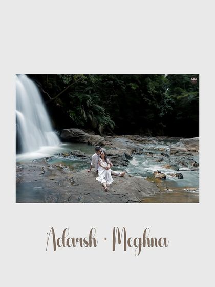 A wide shot of the couple at a waterfall, capturing the movement of the water. This is a perfect example of an adventurous and scenic pre-wedding shoot.