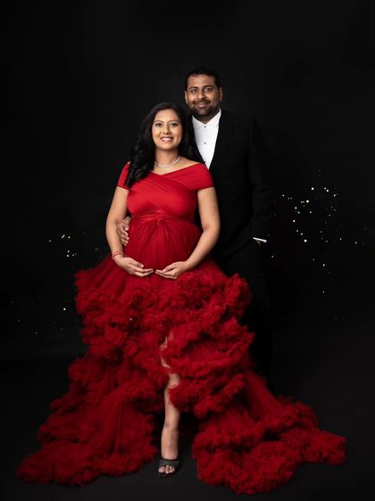 A classic, formal portrait of the happy couple. Her amazing red gown and his sharp suit make for a very elegant and timeless maternity photo against the dark studio backdrop.