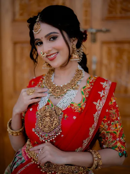A close-up portrait of actress Niveditha Gowda, focusing on her intricate temple jewelry and radiant smile. This shot is perfect for showcasing bridal accessories.