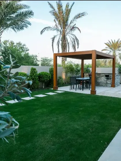 Our backyard site transformation in Noida is complete. The expansive, lush artificial lawn provides a perfect green canvas for the surrounding palm trees and pergola, creating a stunning and low-maintenance outdoor retreat.