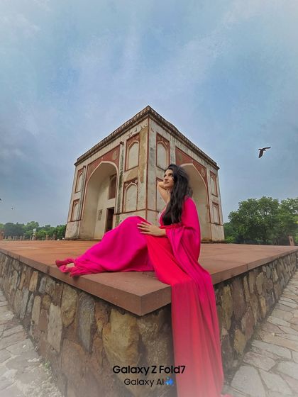 This wide angle shot captures the grandeur of the location and the stunning flow of her bright pink dress. A perfect example of a dramatic, fashion-forward ethnic portrait.