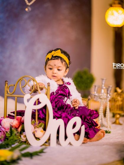 Highlighting the big number one. This setup features a large "One" sign next to a miniature bed prop, set against a soft, dreamy background, perfect for a first birthday milestone photo.