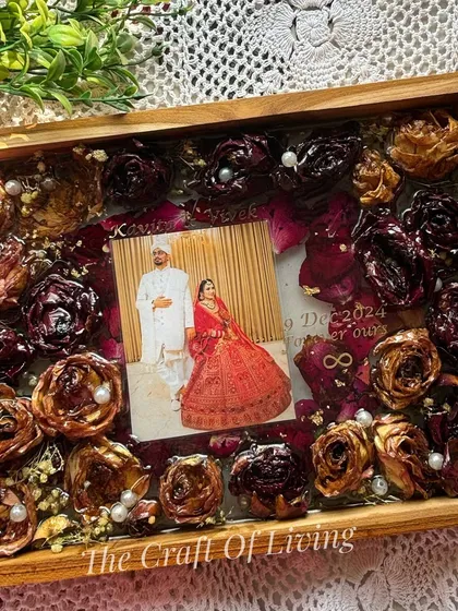 A close-up of a wooden frame filled with beautifully preserved red and brown roses. The detail shows how each flower is carefully placed to create a full and luxurious look.