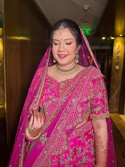 A beautiful bride in a vibrant pink lehenga. Her makeup is luminous and timeless, with a focus on glowing skin and a lip colour that perfectly matches her outfit.