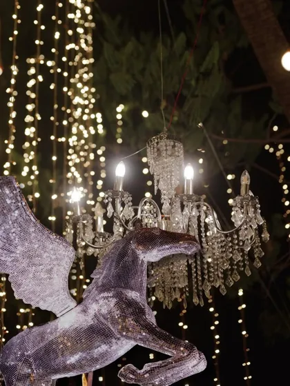 A whimsical decor detail for a Sangeet, featuring a glittering Pegasus statue against a backdrop of fairy lights and chandeliers.