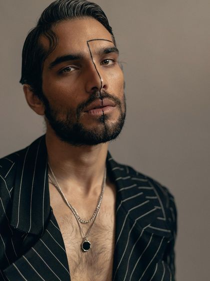 A powerful headshot with graphic makeup, adding an artistic element to the menswear editorial. The styling is kept minimal to let the portrait and concept shine.