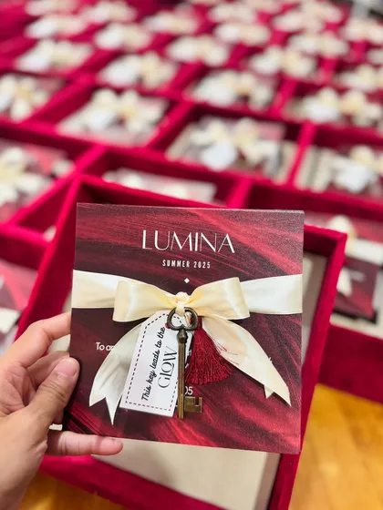 A hand holding the 'LUMINA' event invitation, showcasing the intricate details like the tassel and custom tag. It’s these small, thoughtful touches that elevate a gift from ordinary to extraordinary.