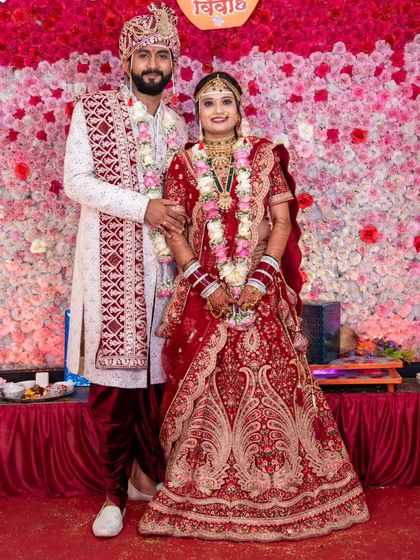 A perfect portrait of the bride and groom on their wedding day. Her traditional red lehenga is beautifully detailed, creating a timeless look.