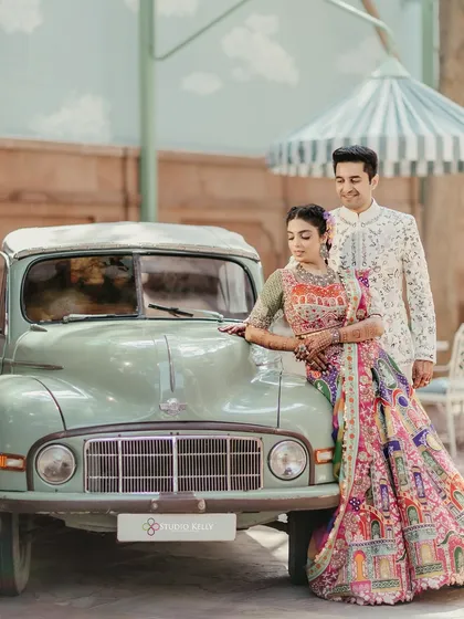 A vintage-inspired pre-wedding shot in Bikaner. The classic car and the bride's intricately detailed lehenga create a nostalgic and regal atmosphere at the Laxmi Niwas Palace.