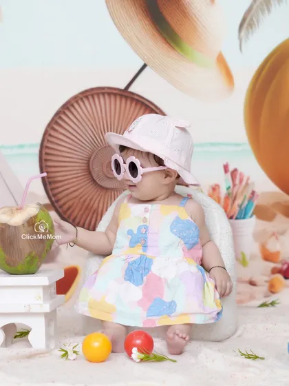 The coolest baby on the beach. Sipping coconut water with stylish sunglasses, this toddler is living the good life in our beach-themed setup.
