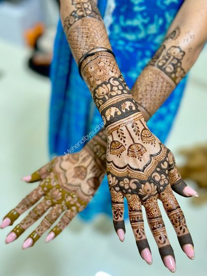 The back of the hands for an engagement mehendi, featuring elephant processions and delicate jhumka designs.