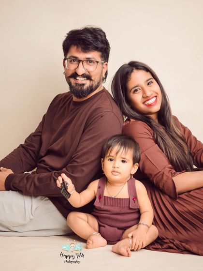 A relaxed, seated family portrait with their little one front and center. The back-to-back pose for the parents is a fun twist on a classic setup.